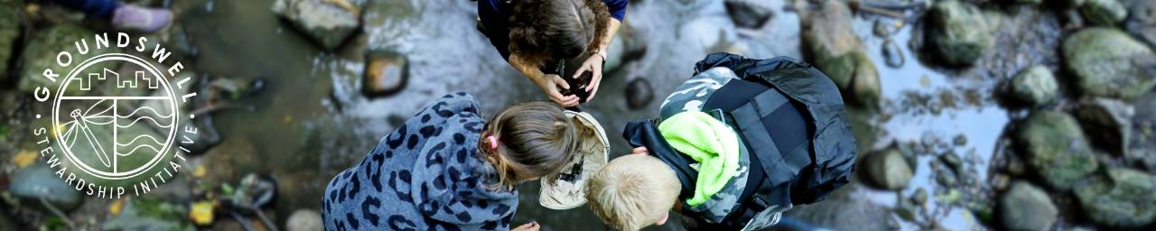 Three students doing water testing in a stream